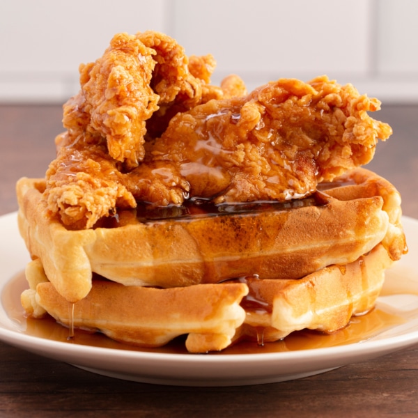 A Pile of Chicken and Waffles on a Rustic Wooden Counter