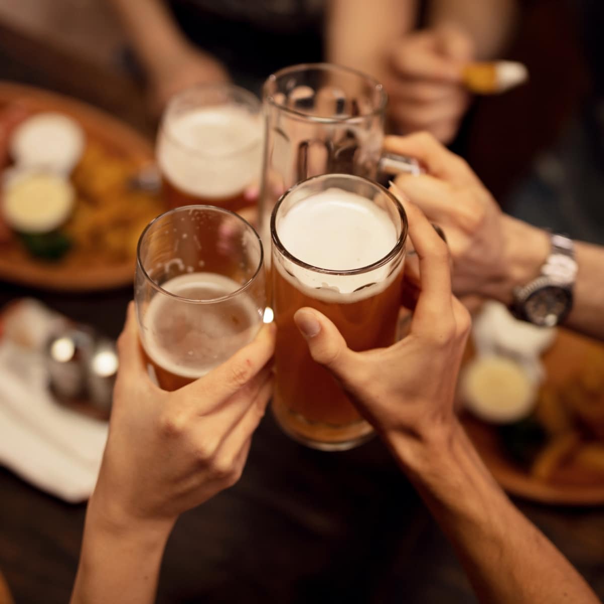 Close up of friends toasting with beer and having fun in a pub.