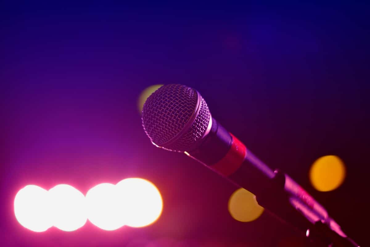 Colorful stage lighting highlights a microphone in a close-up view, perfect for music and performance themes.