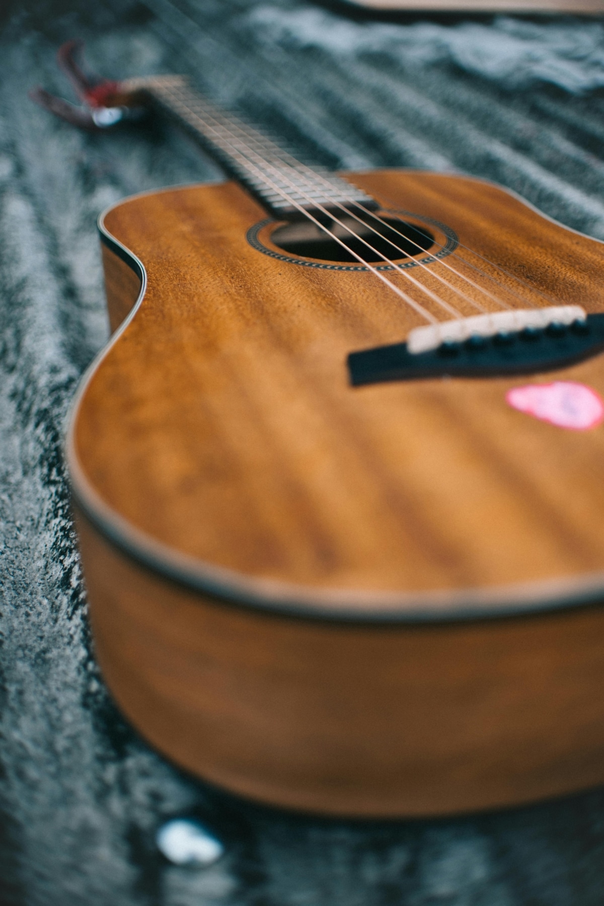 Detailed close-up of a wooden acoustic guitar with strings and pick in view.