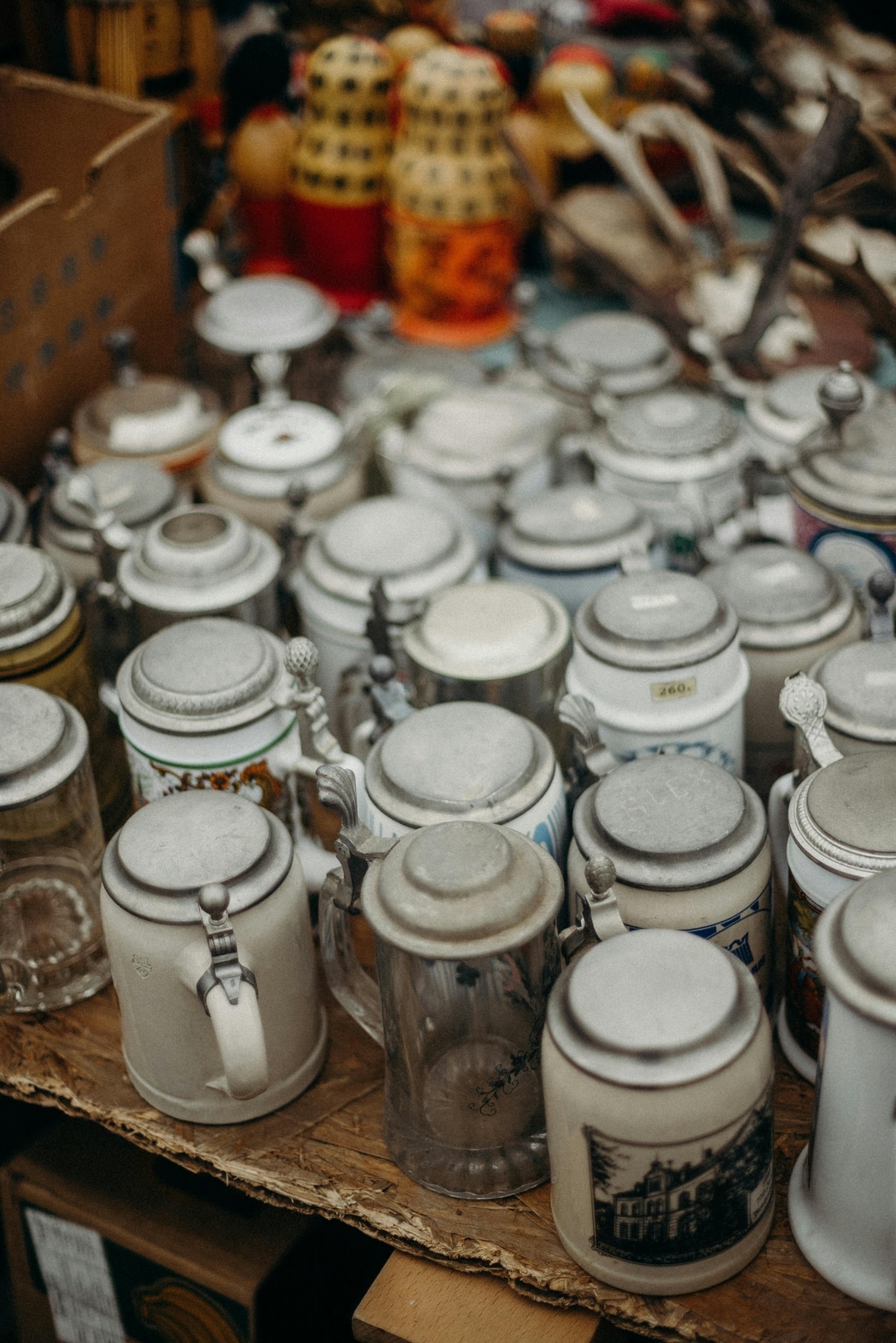 A close-up view of vintage ceramic beer steins displayed at a flea market or swap meet.